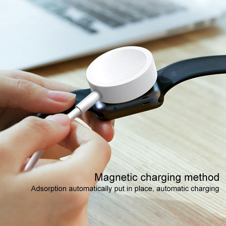 White magnetic charging puck for a watch with cable, held by fingers