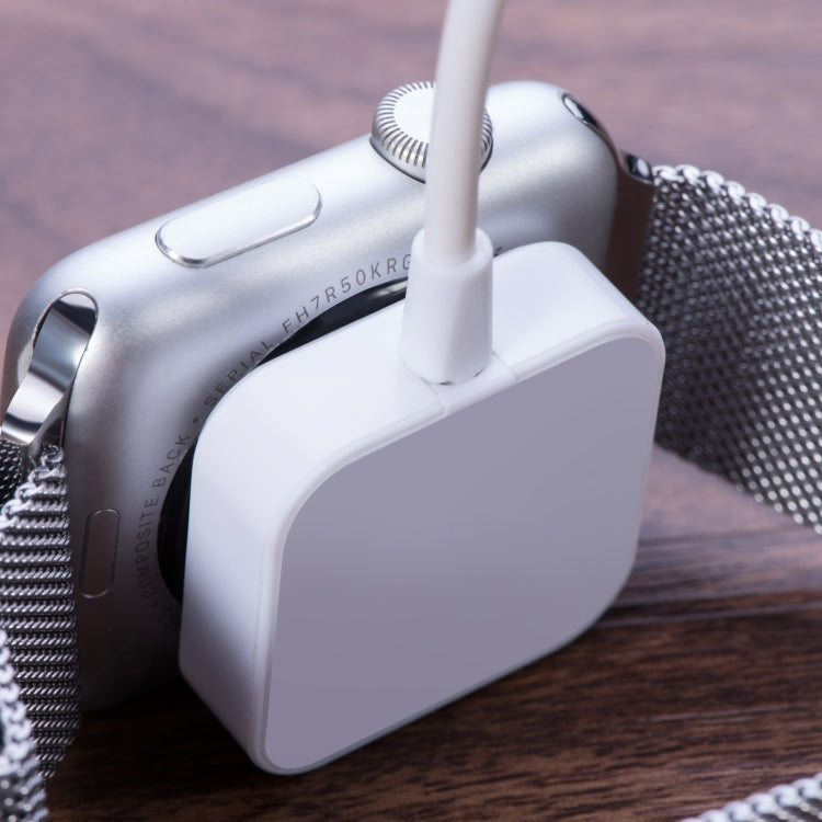 Square white charging puck magnetically attached to smartwatch on metal strap