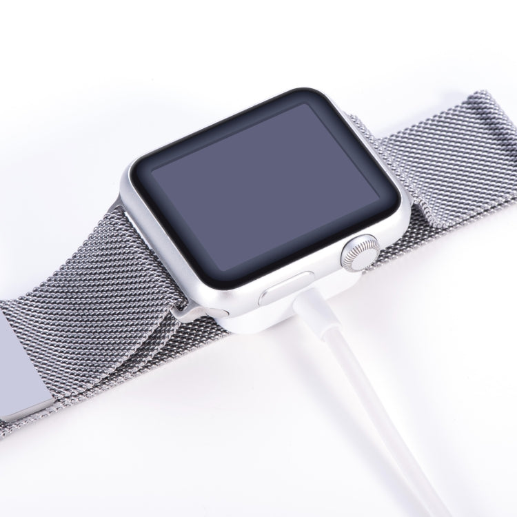 White charging cable end with square puck connected to smartwatch on mesh strap