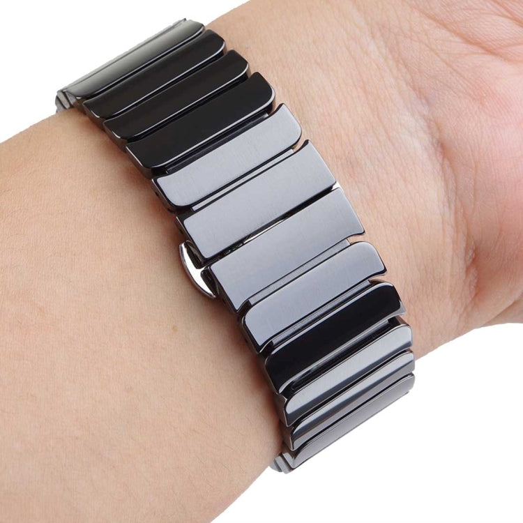 Two-tone black and silver ceramic Apple Watch band worn on wrist