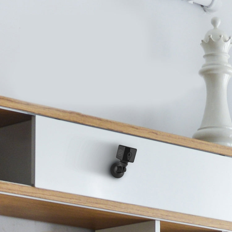 Wireless surveillance camera on a small wall-mounted bracket beneath a wood shelf