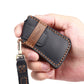 Black leather key fob cover held in hand with metal key ring and tan stitched trim