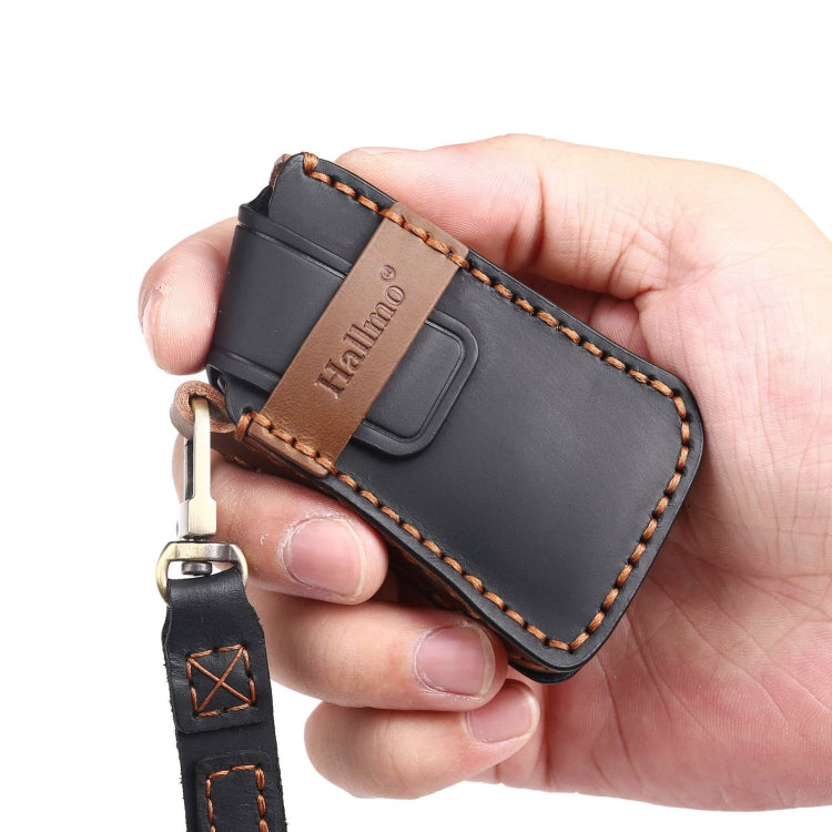 Black leather key fob cover held in hand with metal key ring and tan stitched trim