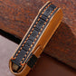 Black leather key fob cover side with key strap, orange topstitching, and button icons