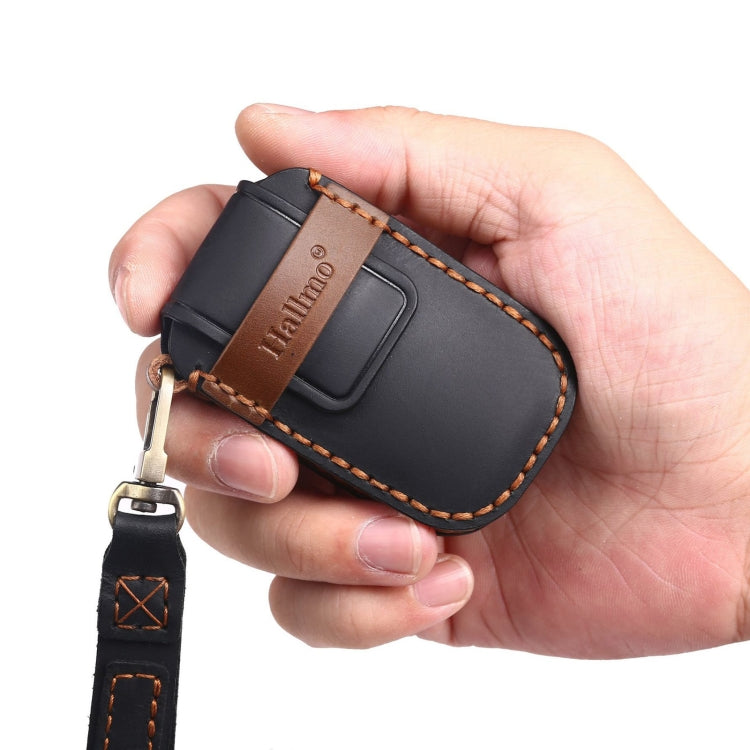 Black cowhide leather car key cover held in hand with metal key ring