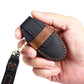 Cowhide leather key fob cover held in hand, black with brown contrast stitching
