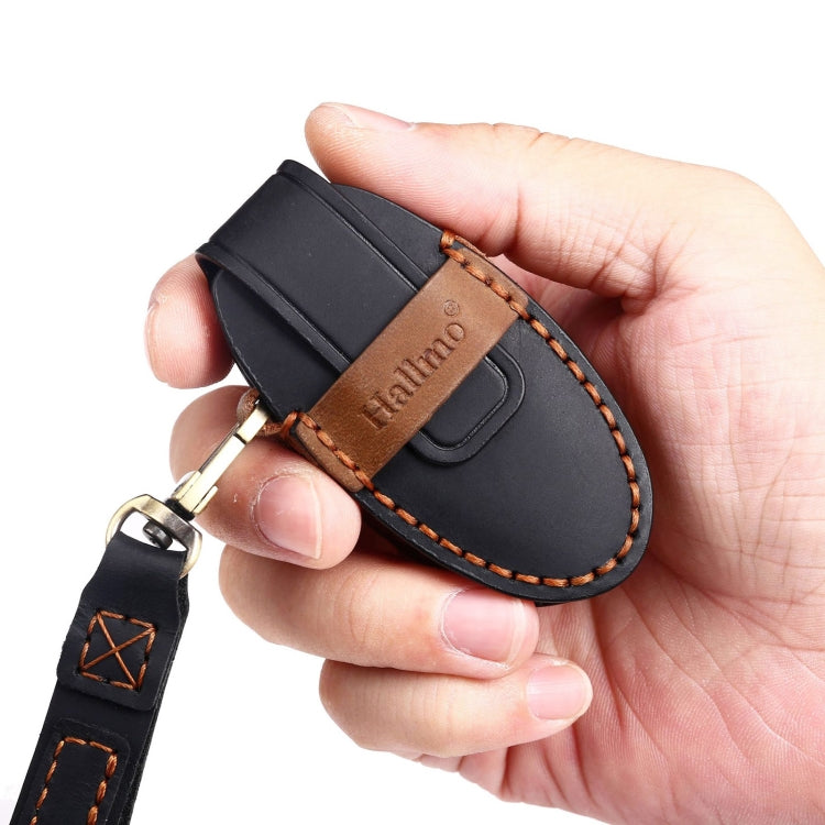 Cowhide leather key fob cover held in hand, black with brown contrast stitching