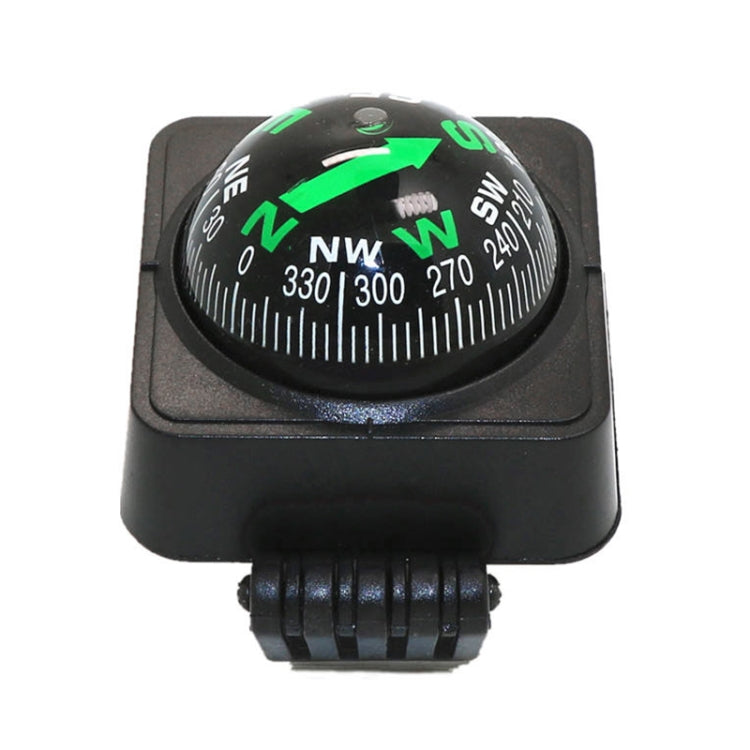 Black dashboard compass ball decoration showing green NW/E/S/W arrows on dial