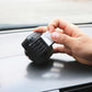 Car compass ball decoration being mounted on dashboard with a hand and sticker pad