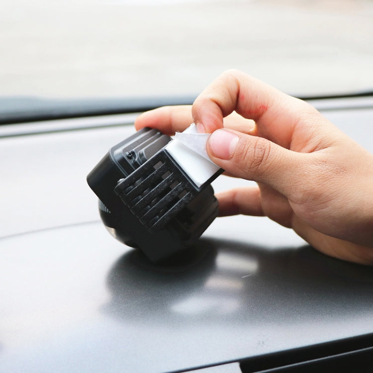 Car compass ball decoration being mounted on dashboard with a hand and sticker pad