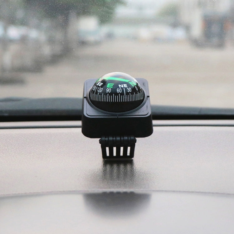 Black dashboard compass ball decoration on windshield with green direction dial