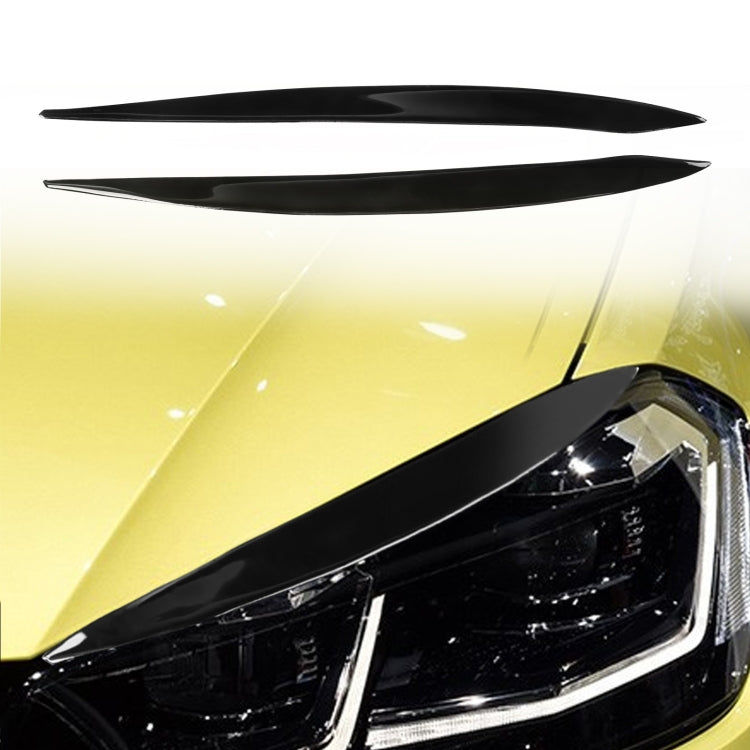 Pair of black headlight eyebrow stickers on a car headlamp, curved slim strips.
