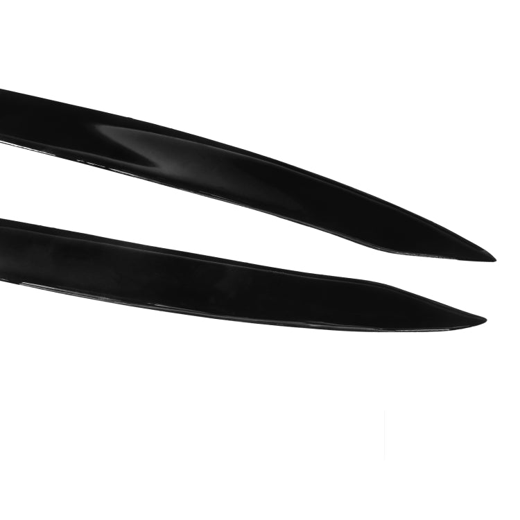 Close-up of two black curved headlight eyebrow sticker strips with glossy finish.