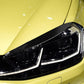 Close-up of black headlight eyebrow stickers on a car headlamp with glossy trim.