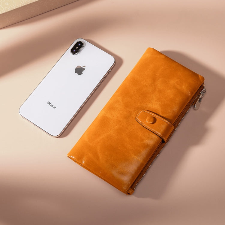 Orange leather wallet with snap front strap and gold-tone zipper beside phone
