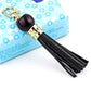 Gold-tone tassel keychain with black bead and black leather tassel strands
