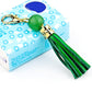 Gold-tone tassel keychain with green bead and green leather tassel strands