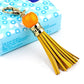 Gold-tone tassel keychain with orange bead and tassel, clip ring clasp