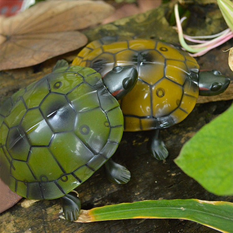 Yellow and green tortoise toy on rocky surface, showing shell pattern and legs.