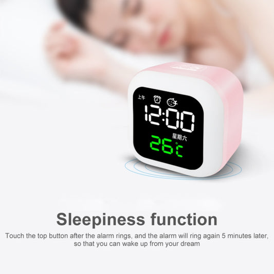 White digital bedside clock with black screen showing 12:00 and 26°C; pink night light glow