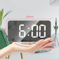 LED mirror clock held in hand with bright 6:00 digits and white base