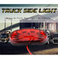 Red oval LED truck side marker light with bright red glow and two mounting holes.