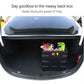 Black folding storage box with compartment panels holding packaged items in car trunk