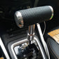 Silver T-shaped gear shift knob with black perforated grip installed in a car
