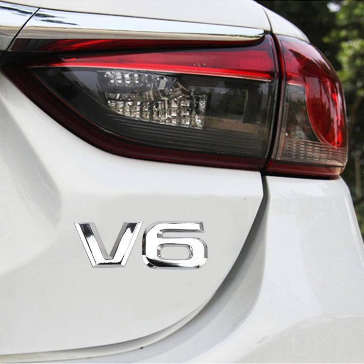 Silver V6 shape metal sticker on rear bumper panel of a car