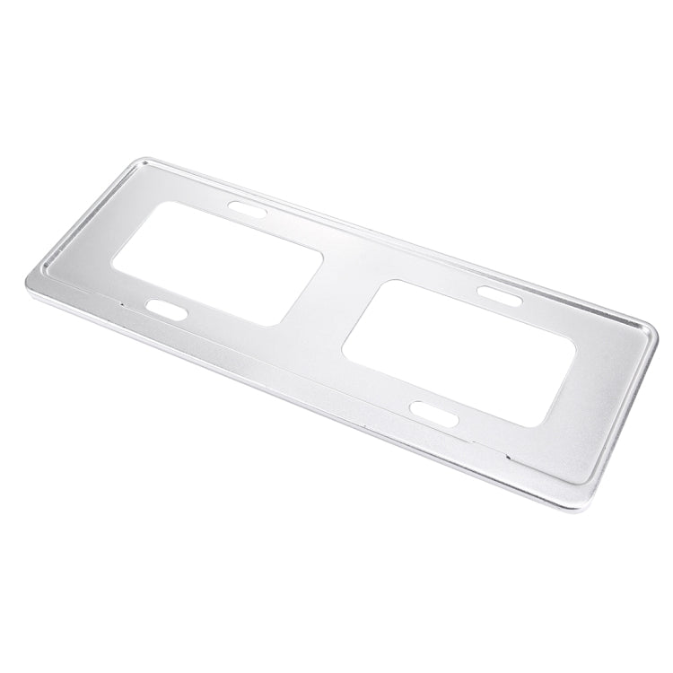 Silver license plate frame holder bracket with rectangular cutouts, angled view