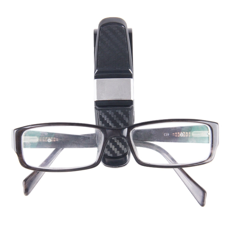 Vehicle mounted glasses clip holding rectangular eyeglasses, black carbon-fiber center