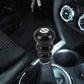 Black gourd-style gear shift knob installed on car center console with white emblem