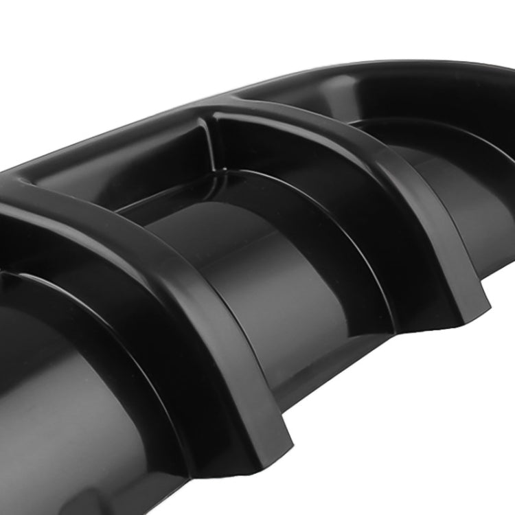 Close-up of black shark-fin style rear bumper lip diffuser with curved fin channels
