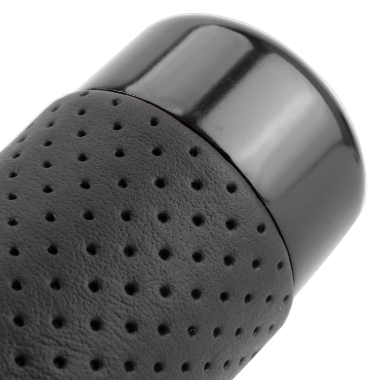Close-up of black perforated leather-textured grip on long car shift knob