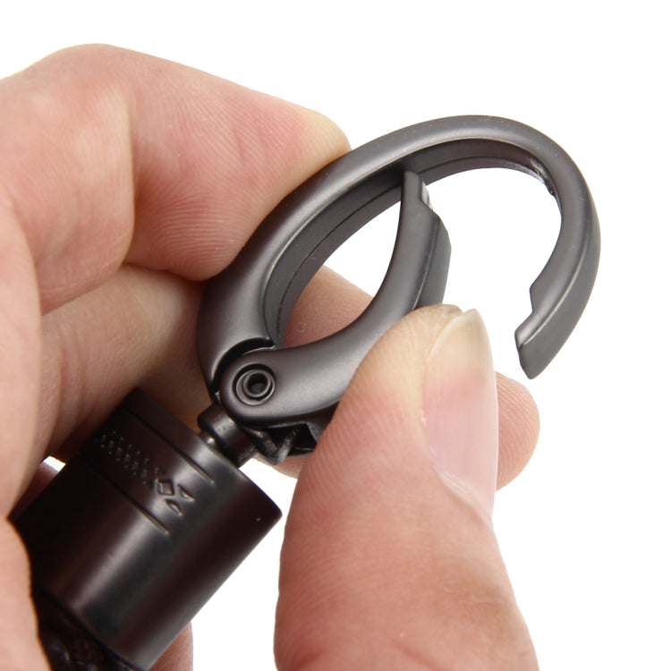 Metal key ring clasp keychain with black braided strap, shown in hands