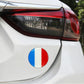 Round France flag sticker on a car rear bumper near the taillight