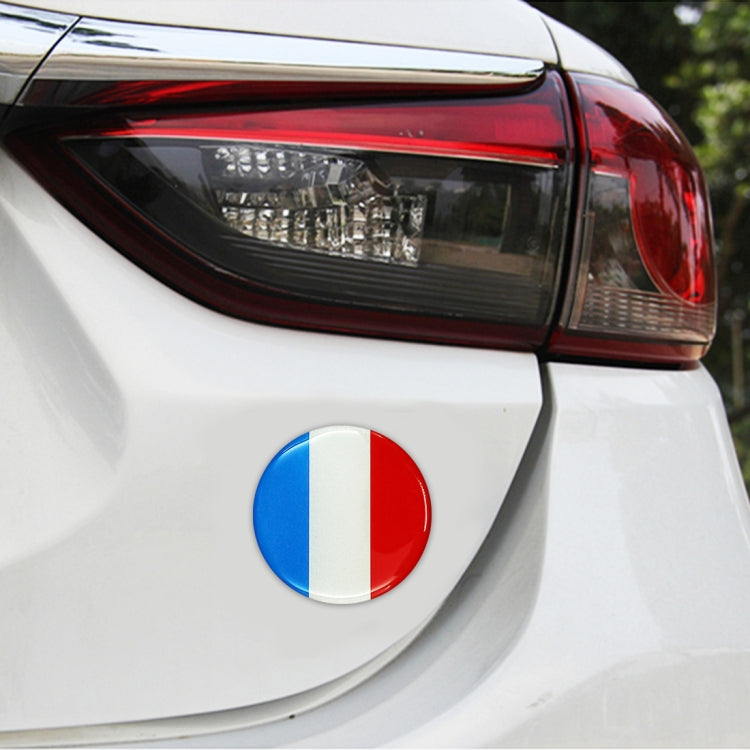 Round France flag sticker on a car rear bumper near the taillight