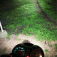Motorcycle headlight beam illuminating grass and gravel path at night