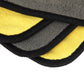 Microfiber cleaning towel edge close-up, yellow and gray layers with black binding.