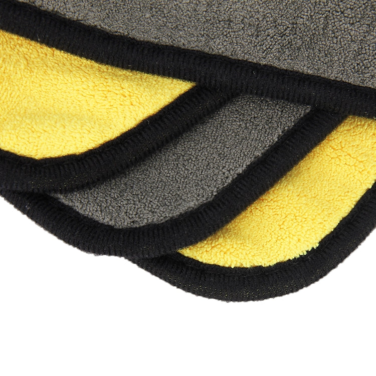 Microfiber cleaning towel edge close-up, yellow and gray layers with black binding.