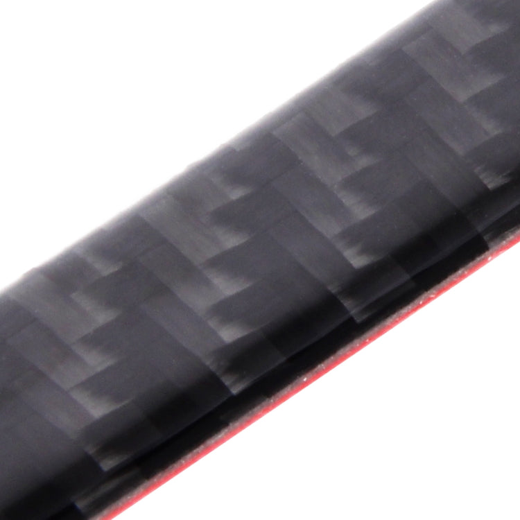 Close-up of black carbon fiber door edge guard with red trim strip along the edge.