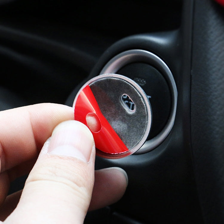 Red and black engine start/stop button cover being pressed onto a car button
