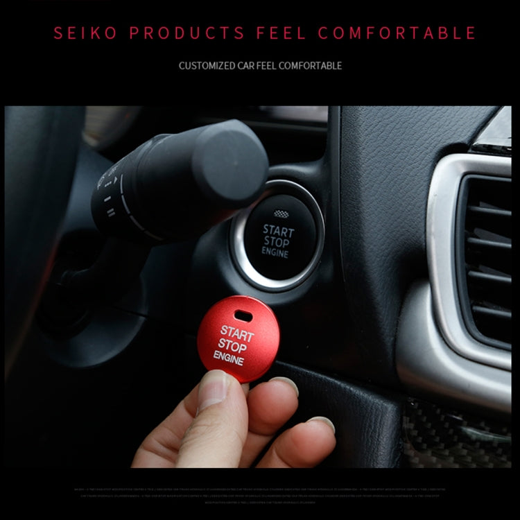 Red engine start stop button cover held near a car ignition start/stop button