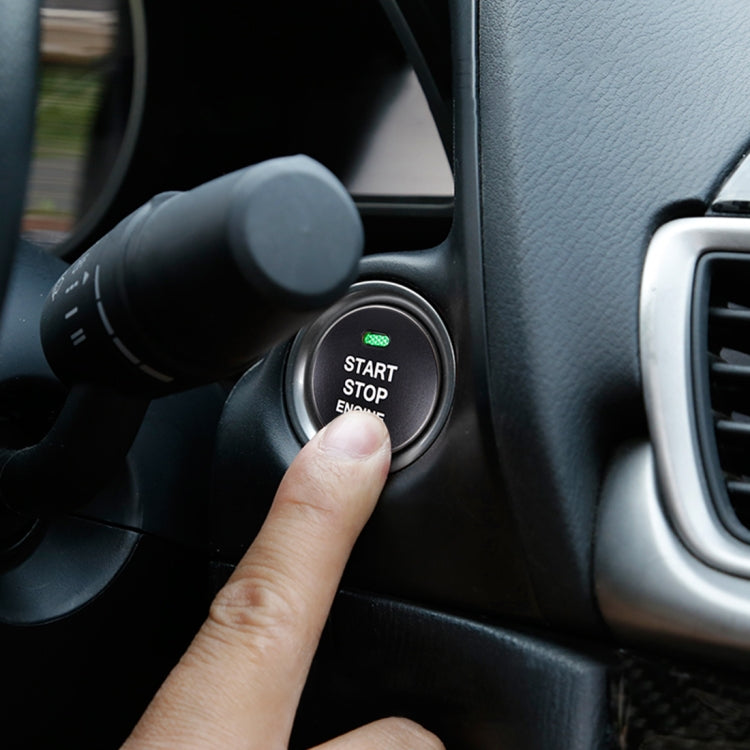 Black round engine start stop button cover on car dashboard with finger pointing