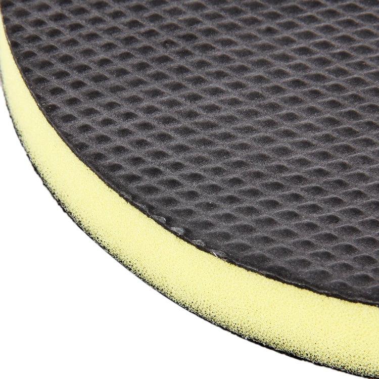 Close-up of round black grinding pad with yellow foam backing and textured face