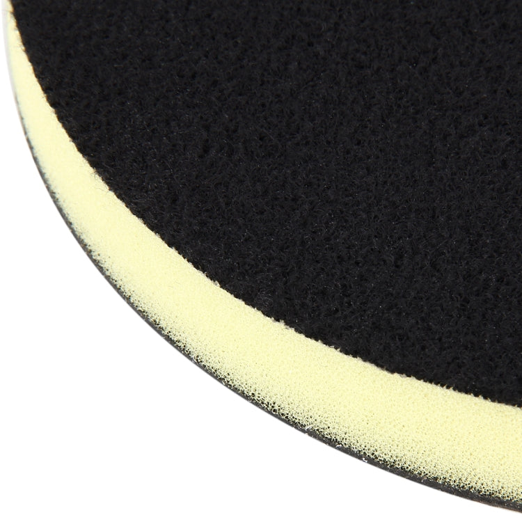 Close-up edge view of black grinding pad with yellow foam backing strip