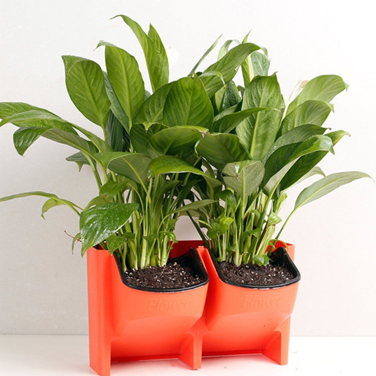 Orange stackable planter with two black pots holding green leafy plants