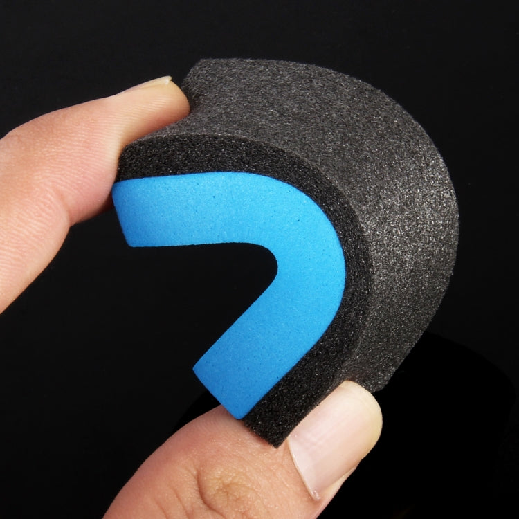 Hand holding a dark gray abrasive pad with blue foam inner section