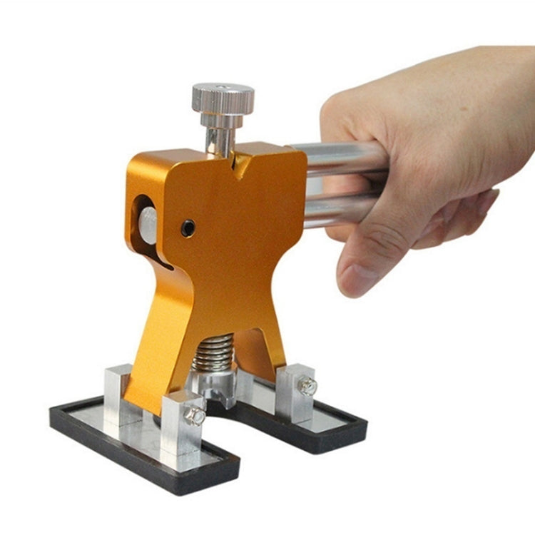 Hand holding orange dent lifter tab tool on vehicle panel