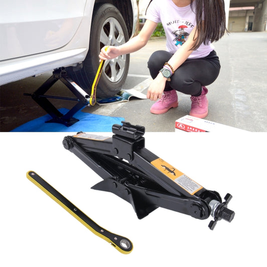 Black scissor jack with yellow handle and lift plate, set under a car tire